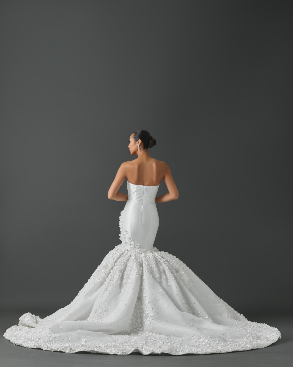 Strapless mermaid gown with soft scoop in neckline into points. Clean fitted silhouette into full gathered mermaid. Embellishment on gown features tiny roses dotted with crystals and pearls. This detail is heavy on the mermaid of the gown and blends onto the body on one side towards the hip.