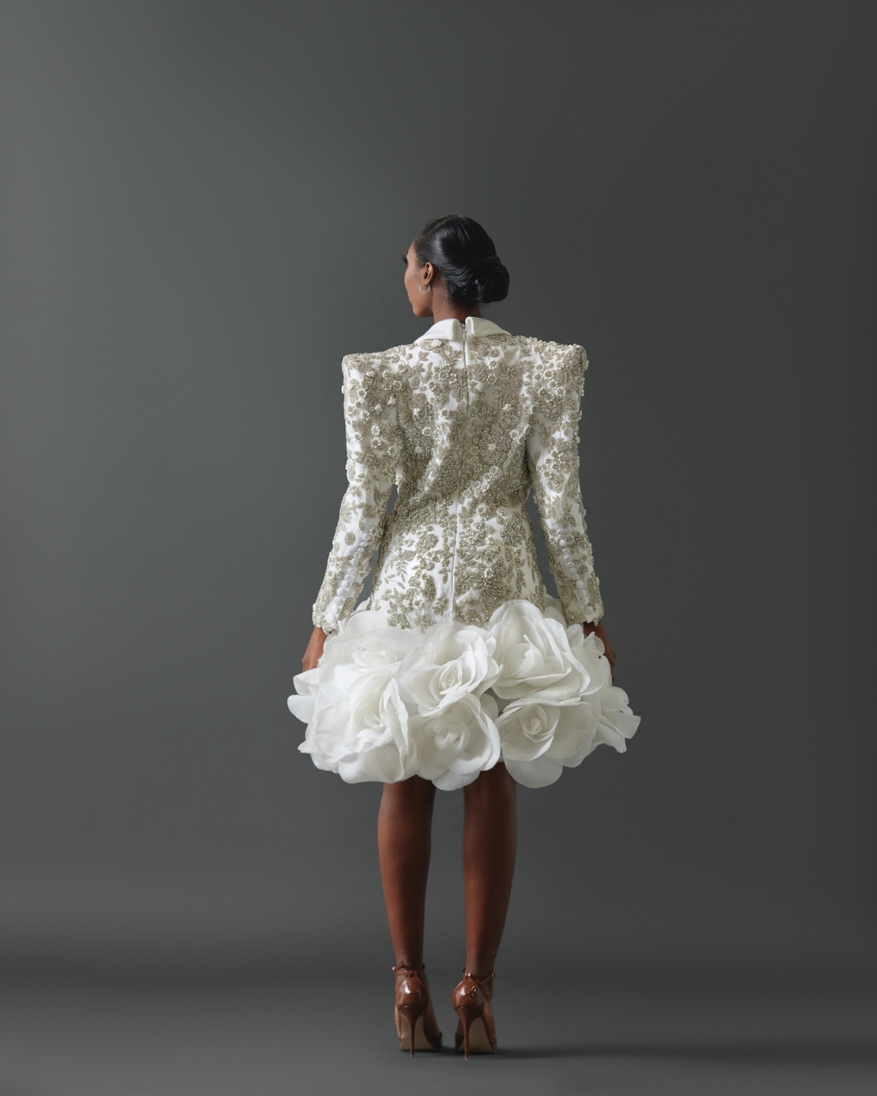 Mini dress comprised of tuxedo jacket with structured shoulders. Entire jacket encrusted with signature crystal and floral applique framed by clean lapel. Skirt of dress featuring large hand-made silk organza rosettes.