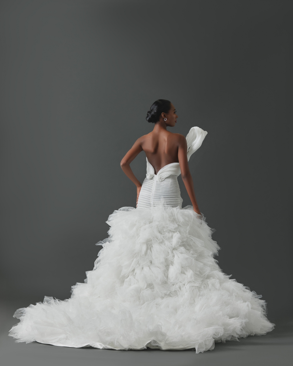 Strapless mermaid gown with structural asymmetrical pleated detail across bodice and pleated tulle framing body. Mermaid skirt constructed with handkerchief cut pieces of tulle.