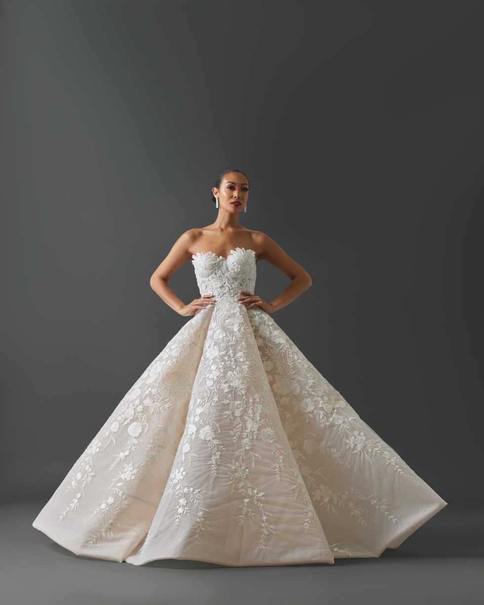 Strapless Aline gown with corseted exposed bodice. Skirt of gown wide structured Aline with deep pleats. Entire gown embellished with embroidered rose patten lace layered on top of glitter tulle.